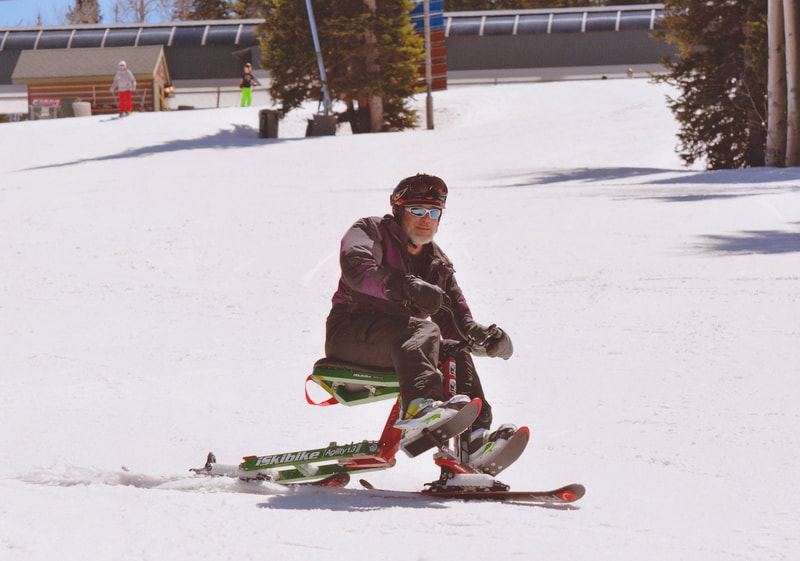 Riding with his festoon the pegs, an adaptive skier shows off his iSkibike at Snowmass, Colorado.