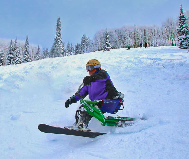 An adaptive ski biker flying out of deep powder on his iSkibike with the Steamboat Powder Cats, Steamboat Springs, Colorado.